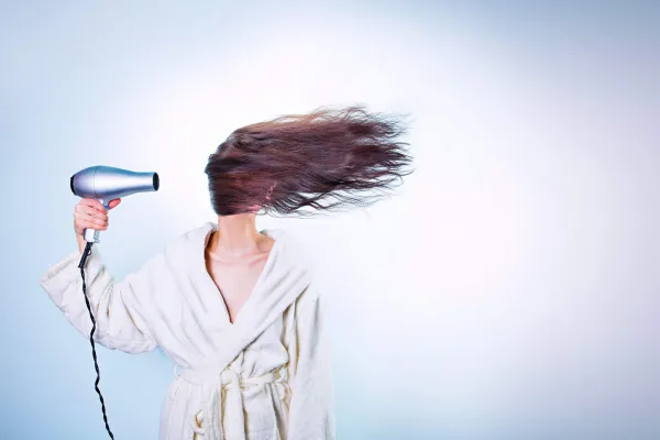 Woman blowing hair across face with hairdryer