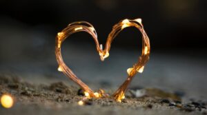 close-up photography of heart shaped fairy lite on brown sand