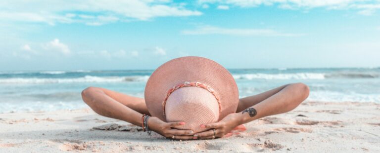 woman in brown sun hat lying on sand during daytime