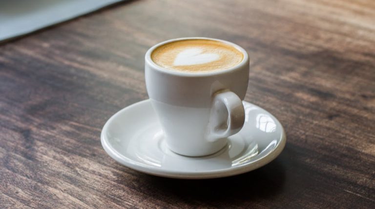 A serene moment with a cappuccino on a wooden table, featuring latte art in a cozy café setting.